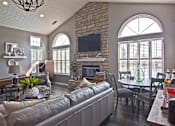 Thumbnail 9 of 21 - A living room with a grey couch and a stone fireplace.