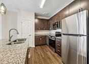 Thumbnail 28 of 51 - A modern kitchen with a granite countertop and stainless steel appliances.