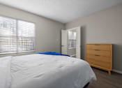 Thumbnail 16 of 67 - A bedroom with a white bed and a wooden dresser.