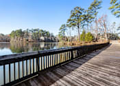 Thumbnail 46 of 50 - A wooden walkway runs alongside a calm body of water.