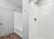 Thumbnail 63 of 64 - A white tiled bathroom with a white door and a white tub.