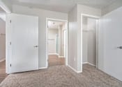 Thumbnail 16 of 28 - A hallway with white doors and a carpeted floor.