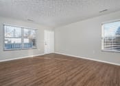Thumbnail 9 of 28 - Empty room with wooden flooring and white walls.