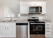 Thumbnail 6 of 28 - A kitchen with white cabinets and a granite countertop.