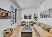 Thumbnail 6 of 25 - A living room with a brown couch, a coffee table, and a large window.