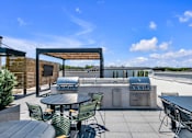 Thumbnail 18 of 25 - A patio with a table and chairs and a grill.