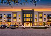 Thumbnail 8 of 25 - A building with the words "Air Lofts" on it is lit up at dusk with cars parked in front.