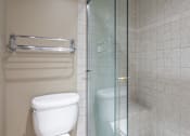 Thumbnail 15 of 33 - A white toilet sits next to a glass shower door in a tiled bathroom.