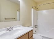 Thumbnail 21 of 26 - A white sink with a wooden counter top and a white bathtub with a shower curtain.