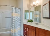 Thumbnail 70 of 88 - A bathroom with a white tub, a white towel, a white sink, a mirror, and a shower curtain.