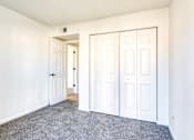 Thumbnail 21 of 56 - A room with a carpeted floor and white walls, featuring a white door and a white closet with a door.