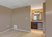 Thumbnail 9 of 33 - A room with beige walls and carpeting, a window with a view of trees, and a cabinet with a countertop.