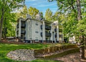 Thumbnail 65 of 67 - A large apartment building with a stone wall in front of it.