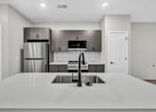 Thumbnail 22 of 27 - A modern kitchen with a stainless steel refrigerator and a white countertop.