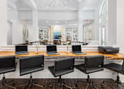 Thumbnail 18 of 20 - A room with a long table and chairs with laptops on it.