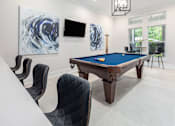 Thumbnail 17 of 20 - A pool table is surrounded by chairs in a room.