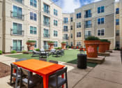 Thumbnail 12 of 60 - an outdoor patio with tables and chairs in front of an apartment building at Proximity at ODU, Norfolk