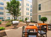 Thumbnail 14 of 60 - an outdoor patio area with tables and chairs at an apartment building at Proximity at ODU, Norfolk, Virginia