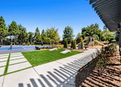 Thumbnail 10 of 34 - A sunny day at the park with a basketball court and trees.