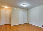 Thumbnail 9 of 21 - an empty living room with wood flooring and white doors