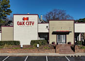 Thumbnail 11 of 29 - The front of the Oak City Apartments building is shown with a clear blue sky in the background.