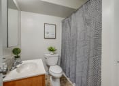 Thumbnail 13 of 22 - a bathroom with a white sink and toilet and a shower curtain