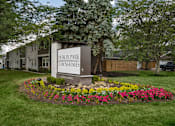 Thumbnail 1 of 31 - A sign for Dublin Park Townhomes is surrounded by flowers and greenery.