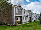 Thumbnail 2 of 31 - A row of houses with a blue sky and clouds in the background.
