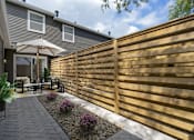 Thumbnail 12 of 31 - A patio with a wooden fence and a table with chairs.