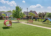 Thumbnail 29 of 31 - A playground with a red slide, a blue slide, and a brown bench.