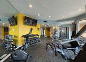 Thumbnail 26 of 31 - A gym with a yellow wall and a row of treadmills.