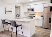 Thumbnail 8 of 31 - A kitchen with a white countertop and a fridge.