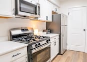 Thumbnail 9 of 31 - A modern kitchen with a stove, microwave, and refrigerator.