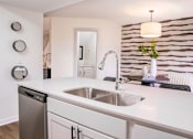 Thumbnail 10 of 31 - A modern kitchen with a white countertop and a stainless steel dishwasher.