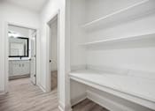 Thumbnail 25 of 56 - A white hallway with a mirror and a bench.