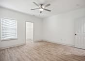 Thumbnail 26 of 56 - A room with a ceiling fan and light, hardwood floors, and white walls.