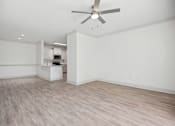 Thumbnail 20 of 56 - A room with a ceiling fan and light fixture, and a kitchenette in the background.