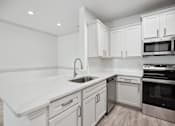 Thumbnail 19 of 56 - A modern kitchen with white cabinets and stainless steel appliances.