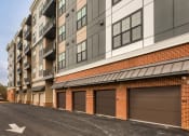 Thumbnail 23 of 38 - a brick building with brown garage doors on a street at Aura Stonebridge, Virginia