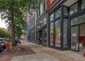 Thumbnail 42 of 46 - a city street with a bench and cars parked on the side of the road