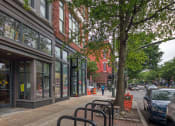 Thumbnail 43 of 46 - a city street with a bench in front of a building