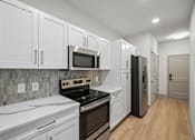 Thumbnail 33 of 59 - A kitchen with white cabinets and a black fridge.
