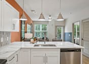 Thumbnail 24 of 59 - A kitchen with a white counter top and a stainless steel dishwasher.