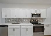 Thumbnail 34 of 59 - A kitchen with white cabinets and appliances.