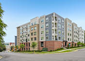 Thumbnail 59 of 59 - A large apartment building with a parking lot in front.