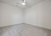 Thumbnail 29 of 59 - A room with a ceiling fan and carpeted floor.