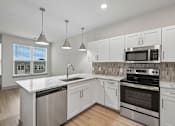 Thumbnail 32 of 59 - A modern kitchen with white cabinets and stainless steel appliances.