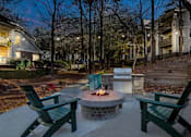 Thumbnail 58 of 67 - A fire pit in the middle of a patio surrounded by two chairs.