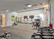 Thumbnail 30 of 33 - A gym with a variety of equipment including dumbbells, a bench, and a treadmill.