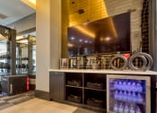 Thumbnail 19 of 38 - a fitness center with a large screen tv and a counter with water bottles at Aura Stonebridge, Virginia